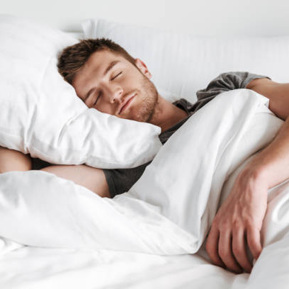 Man sleeping in bed with white bedding and pillows.